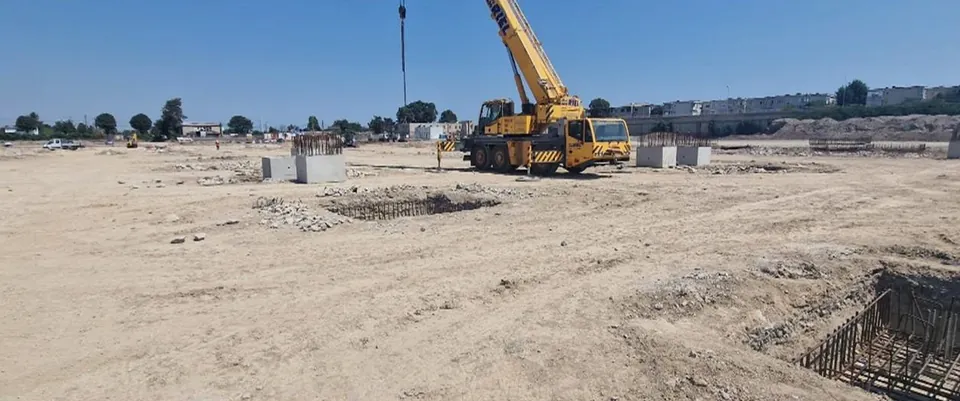 Șantierul magazinului Dedeman Constanța în faza de fundații: macara mobilă, fundații izolate de beton și armături în săpături