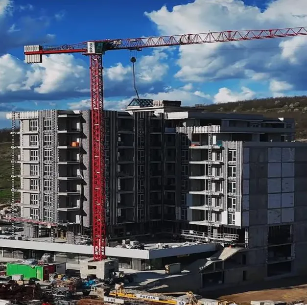 Ansamblul rezidențial Rosetti din Iași în execuție: structura de beton armat a unui bloc cu macara-turn roșie, sub cer albastru cu nori